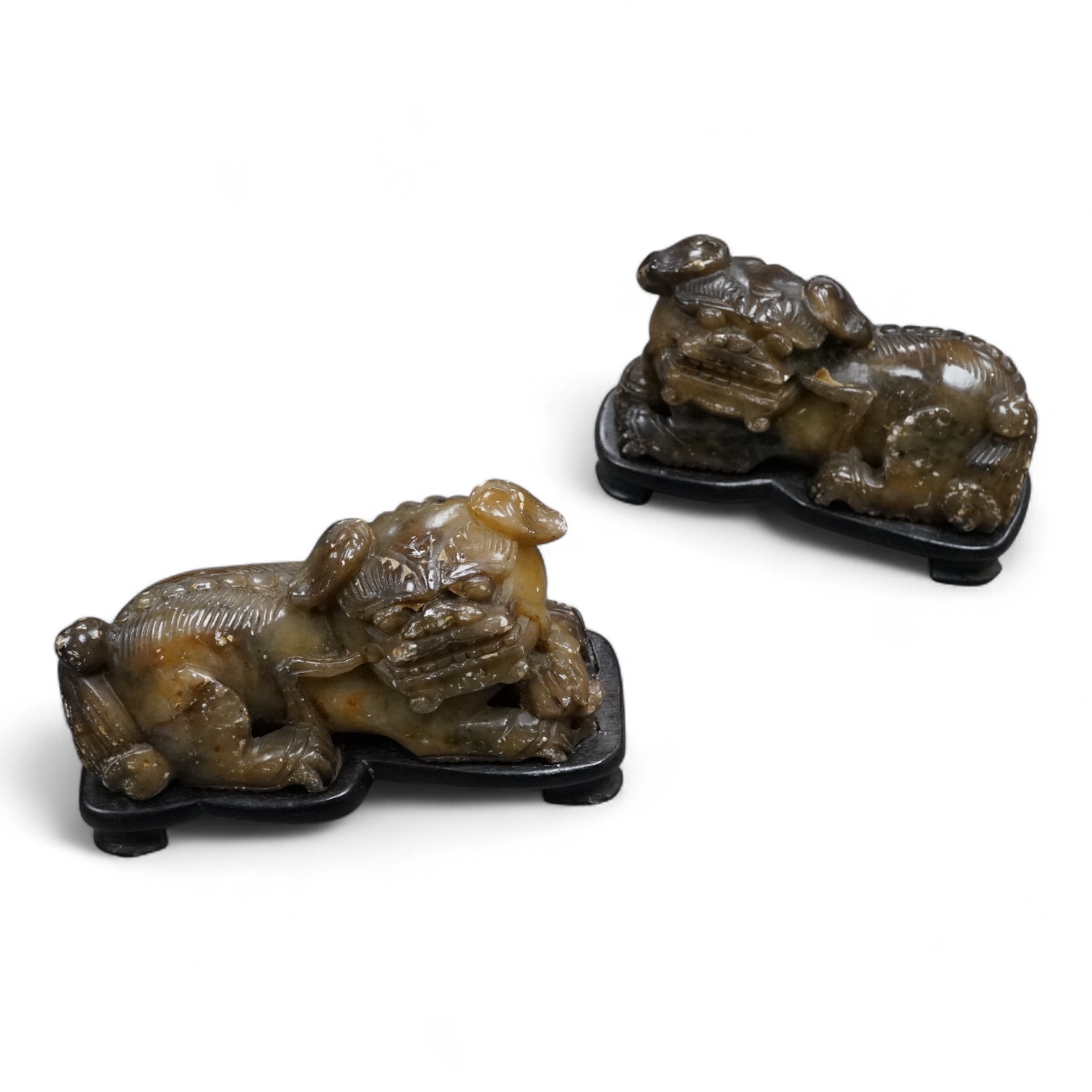 A pair of Chinese soapstone figures of lion dogs, on wood stands, 11cm wide